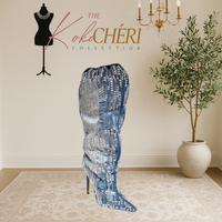 Blue sequin boot on a mannequin with 'The Koki Chéri Collection' branding, indoor setting with plant and chandelier.