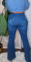 Person wearing blue flared jeans and a matching top in an indoor setting.