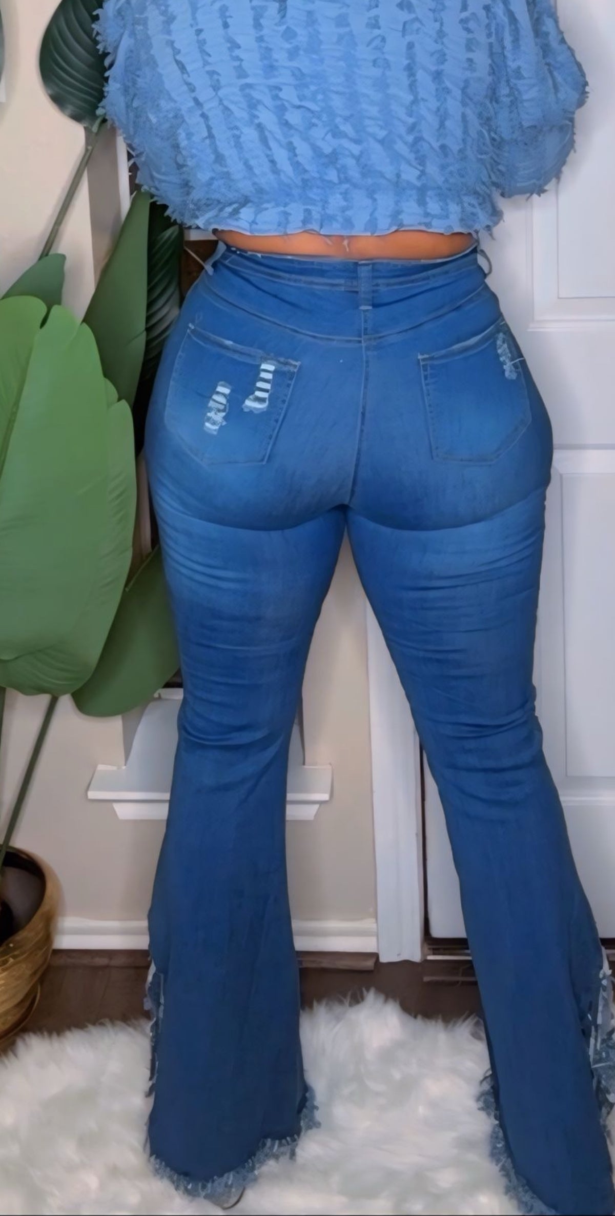 Person wearing blue flared jeans and a matching top in an indoor setting.