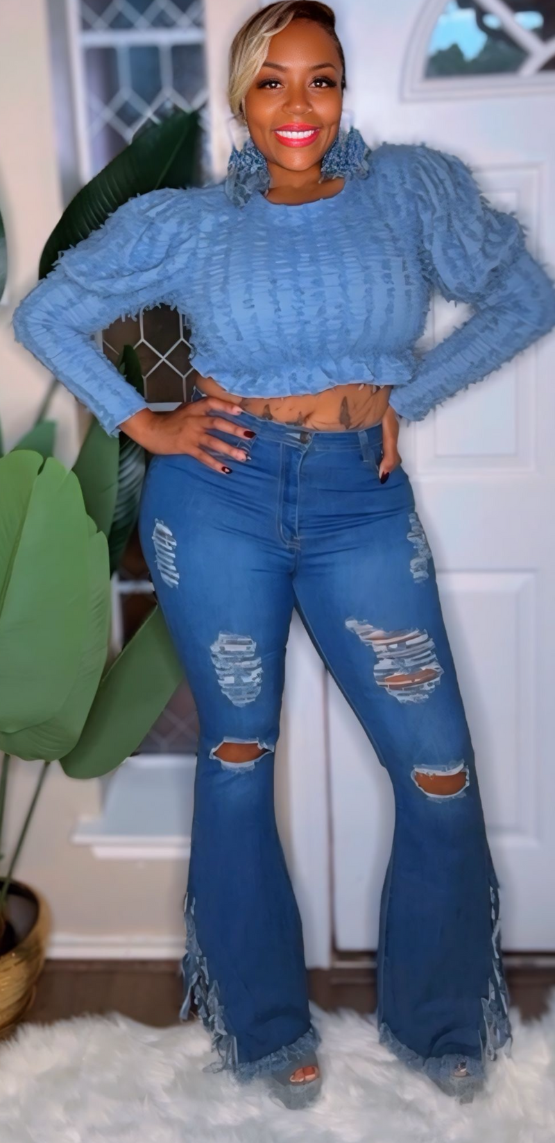 Person wearing a blue ribbed sweater and distressed jeans indoors.